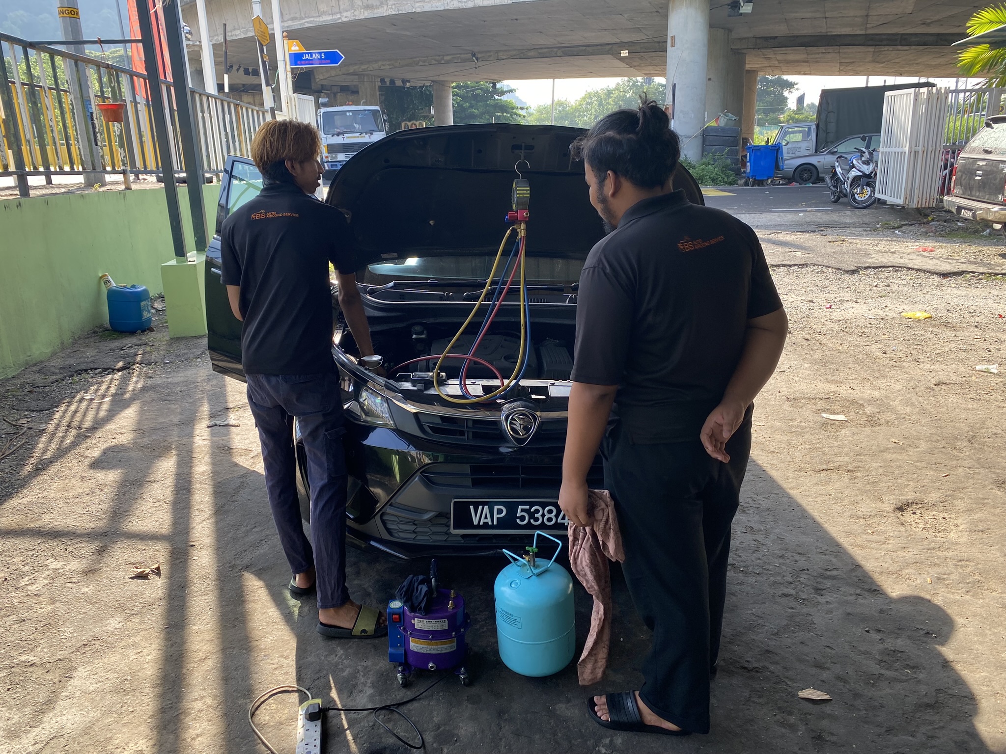Mechanics at a shop near Batu Caves in Kuala Lumpur recharge a car with refrigerant. The gas being used here is HFC-134a, a greenhouse gas thousands of times more potent than carbon dioxide. Photo: Tilden Chao, 2023.